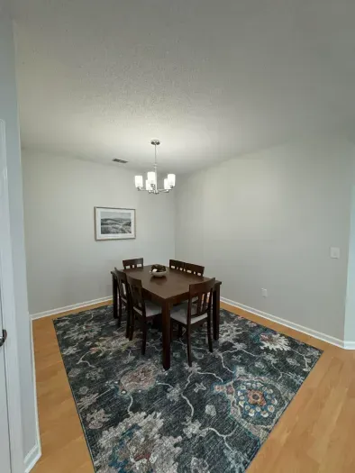 Bright dining nook with 6‑seat table, statement rug, and modern chandelier.