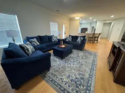 Bright open-plan living with navy sofas, rug, and breakfast bar