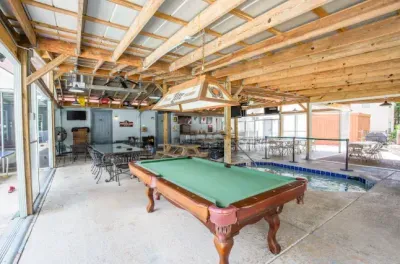 Covered game lounge with pool table, bar, TVs, and a heated plunge spa.