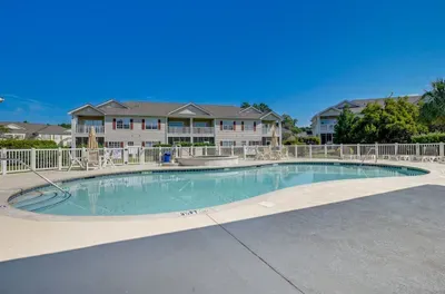 Resort-style pool with loungers, umbrellas, and sunny deck relaxation