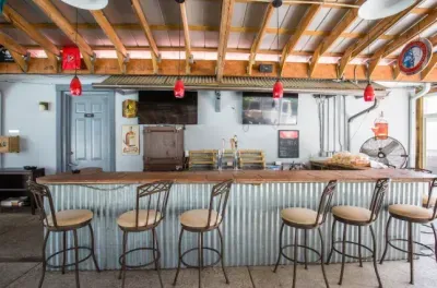 Rustic open-air bar with draft taps, TVs, and comfy counter seating