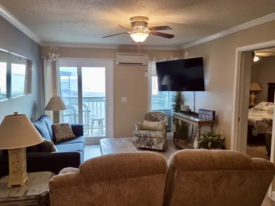 Cozy beach-style living room with balcony access and large TV