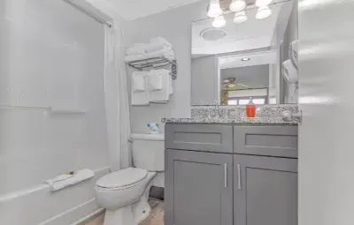 Bright modern bathroom with granite vanity and tub-shower combo