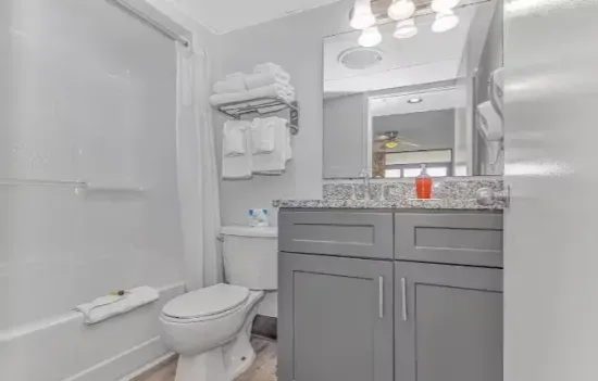 Bright modern bathroom with granite vanity and tub-shower combo
