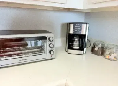 Bright kitchen counter with coffee maker, toaster oven, and tidy prep space