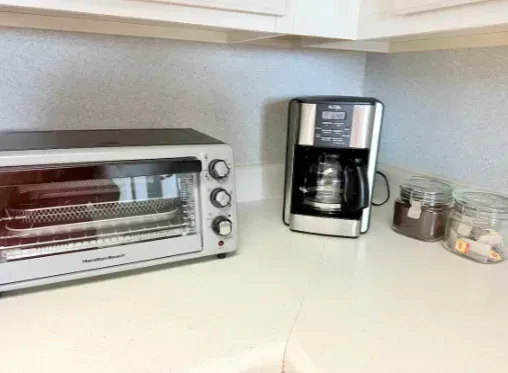 Bright kitchen counter with coffee maker, toaster oven, and tidy prep space