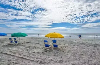 Relax on the wide sandy beach with umbrella chairs and ocean views