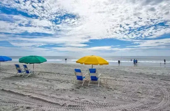Relax on the wide sandy beach with umbrella chairs and ocean views