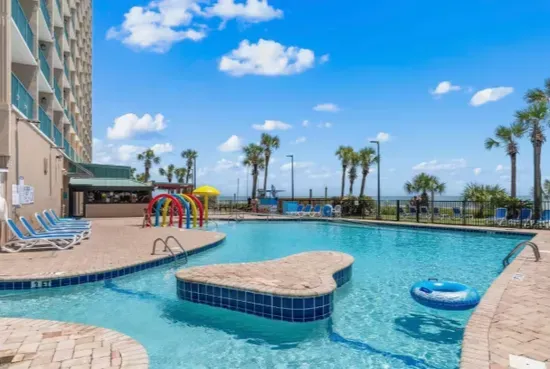 Resort-style beachfront pool with palm views and spacious sun deck