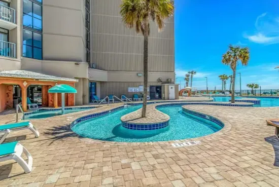 Resort-style pool deck with palm trees and sunny tropical vibes