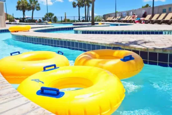 Sunny resort-style pool with float tubes, loungers, and tropical vibes