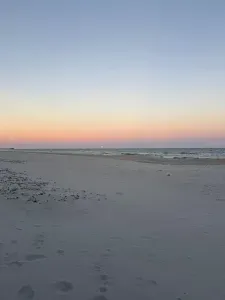 Serene beachfront: endless white sand, pastel skies, calm waves