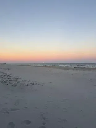 Serene beachfront: endless white sand, pastel skies, calm waves