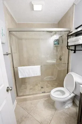 Bright tiled bath with glass walk-in shower and plush towels