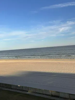 Unobstructed oceanfront vista over a wide, tranquil sandy beach.