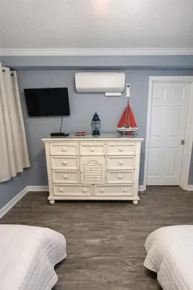 Cozy twin room with TV, AC, and coastal charm—sleep in comfort.
