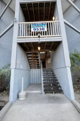 Well-lit, covered entry with palm landscaping—easy condo access