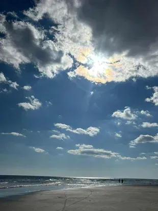 Wide, peaceful beach with sparkling surf and dramatic skies steps away