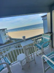 Covered oceanfront balcony with sweeping beach views, high-top seating