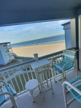 Covered oceanfront balcony with sweeping beach views, high-top seating