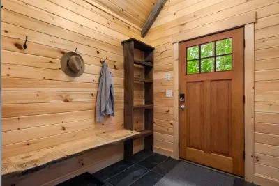 This mudroom features natural wood and tile flooring, creating a cozy feel. A rustic bench offers seating, while shelves and hooks keep coats and essentials organized.