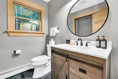 Located on the main floor, the powder room offers a washer and dryer, including detergent, dryer sheets, baskets, and an iron with board for guests. Its efficient design blends practicality with comfort seamlessly.