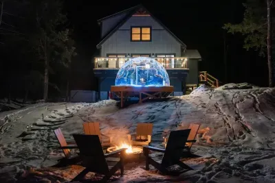 A serene nighttime backyard with golden light pouring from a sleek luxury dome. A glowing fire pit crackles nearby, casting shadows over the steaming hot tub. Warm ambient lighting wraps the scene, creating a cozy, intimate escape under the stars.