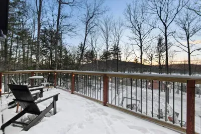 The snowy balcony featurea Adirondack chairs and string lights, offering stunning seasonal views of the lake and mountains.  Below, a luxurious all-season dome provides a cozy retreat for year-round relaxation.