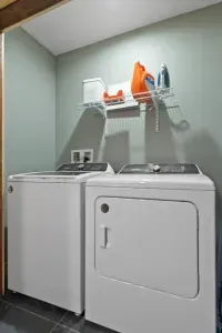 Located on the main floor, the powder room offers a washer and dryer, including detergent, dryer sheets, baskets, and an iron with board for guests. Its efficient design blends practicality with comfort seamlessly.