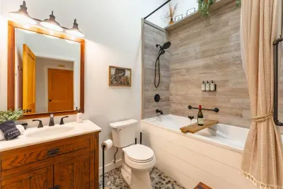 Unwind in the luxurious soaking tub after a day of Pocono adventures. This bathroom features a tub-shower combo with rain-head and handheld options, heated floors, grab bar, and complimentary toiletries at the Pocono Barndominium near Jim Thorpe.