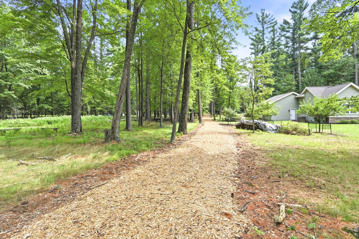 Secluded wooded driveway with mature trees and gray house near Green Bay WI
