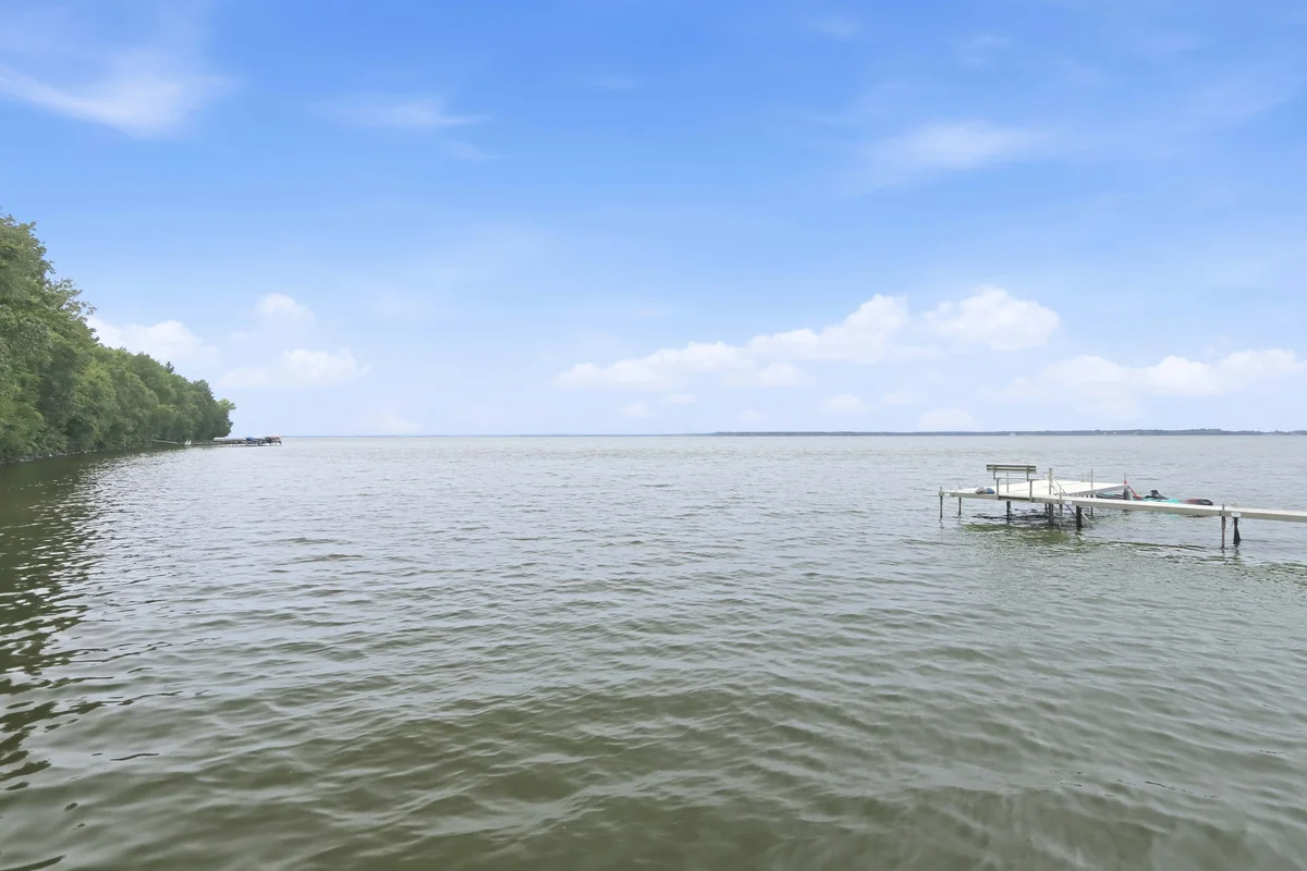 Calm lake with a boat dock on the right and green shoreline foliage under a blue sky, a Central Wisconsin boating spot near