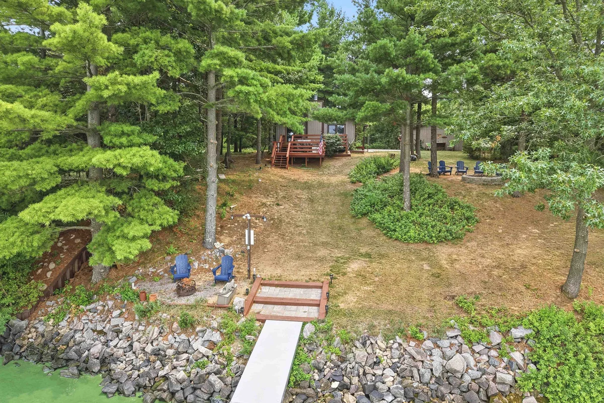 Aerial view of rustic lakeside cabin with dock, fire pit, and pine forest near Lake Petenwell in Nekoosa