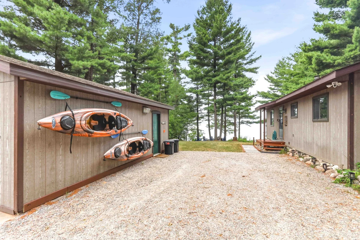 Orange and black kayaks on modern cabin with green trim surrounded by pine trees in Nekoosa Wisconsin