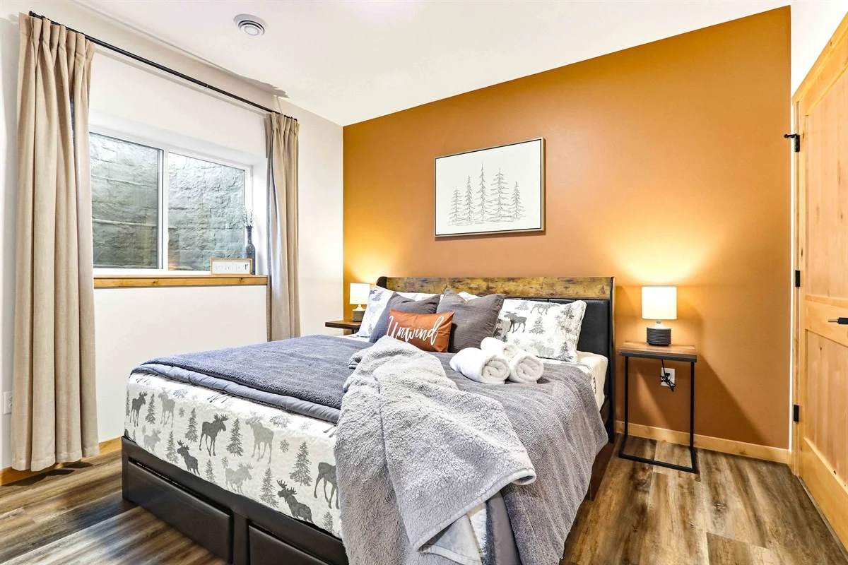 Cozy bedroom with queen bed, wildlife bedding, golden accent wall and forest art at Birdie Bunkhouse, a Nekoosa, WI rental