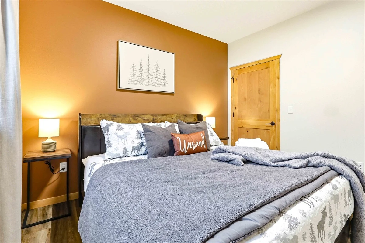 Cozy rustic lodge bedroom with golden walls and wooden furniture at Birdie Bunkhouse near Nekoosa, Wisconsin