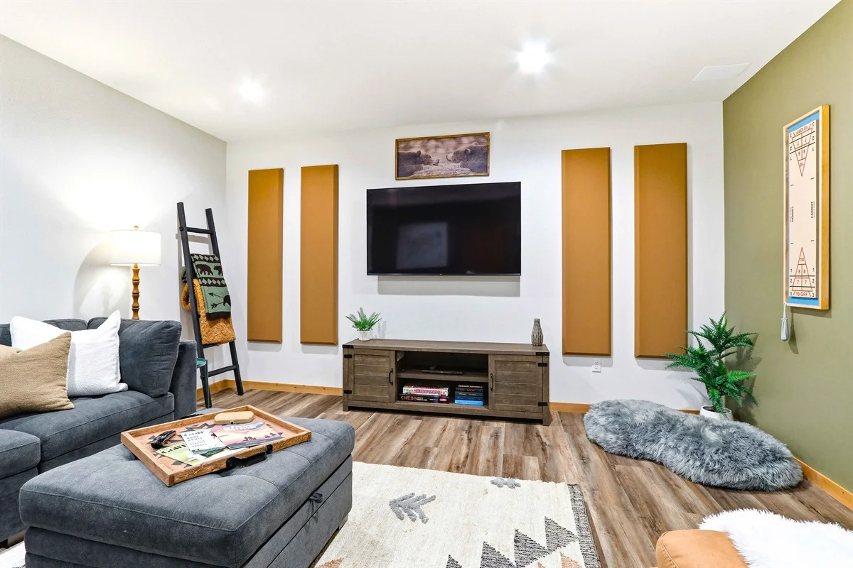 Modern living room with charcoal sectional sofa and mustard olive wall panels in Birdie Bunkhouse, a Clear Trail Properties