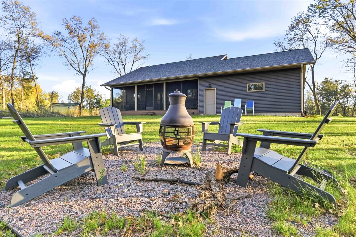 Cabin patio with fire pit and Adirondack seating in Nekoosa vacation rental