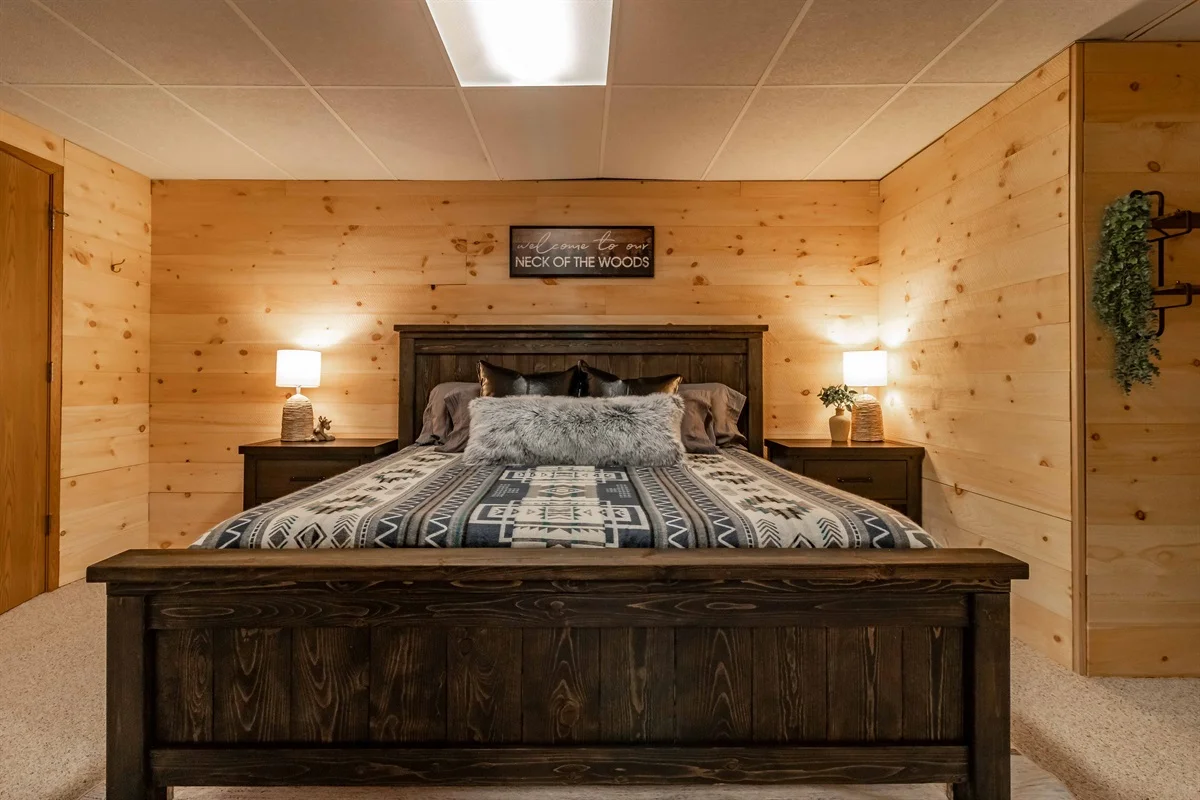 Cozy cabin bedroom with wood paneling, wooden bed frame, and rustic decor at Brown Bear Cabin in Nekoosa, WI