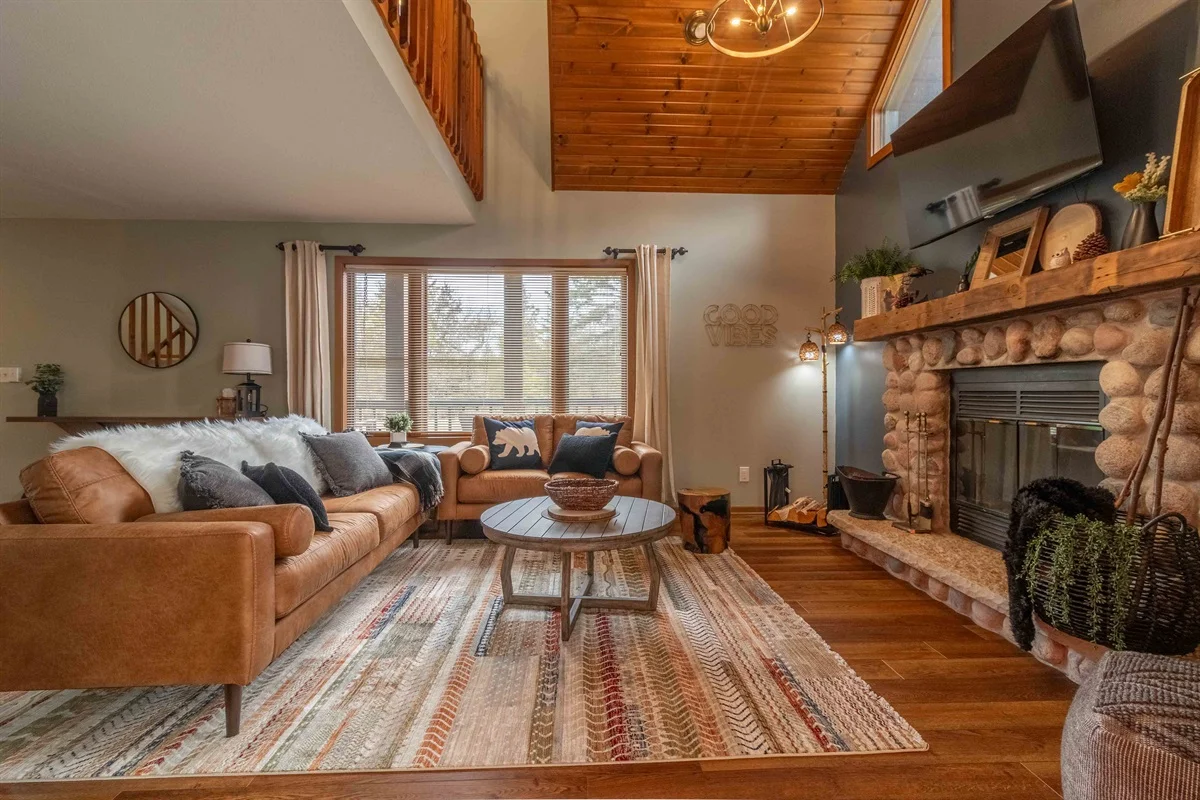Modern rustic living room with cognac leather seating and stone fireplace in Nekoosa, WI vacation rental with private dock
