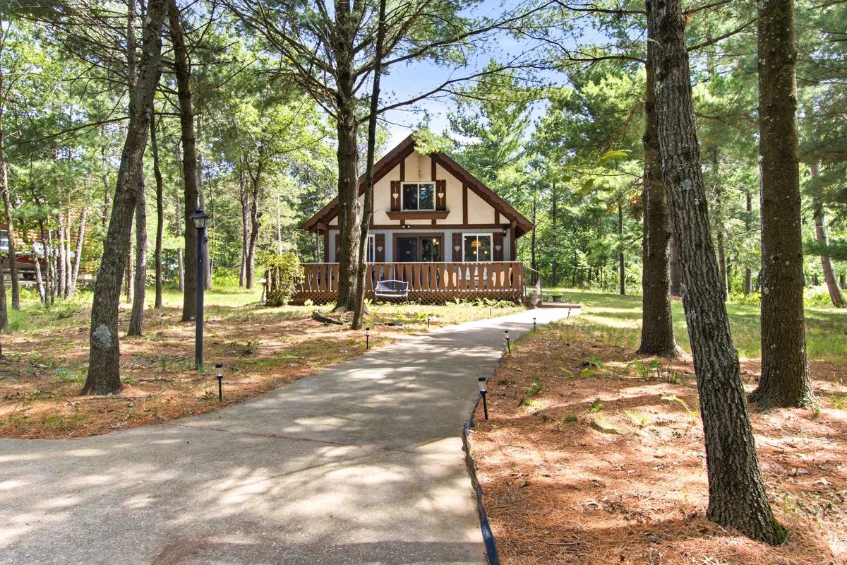 Exterior of Chalet on the Fairway Nekoosa, WI, a tan A-frame chalet among tall pines with a wooden deck