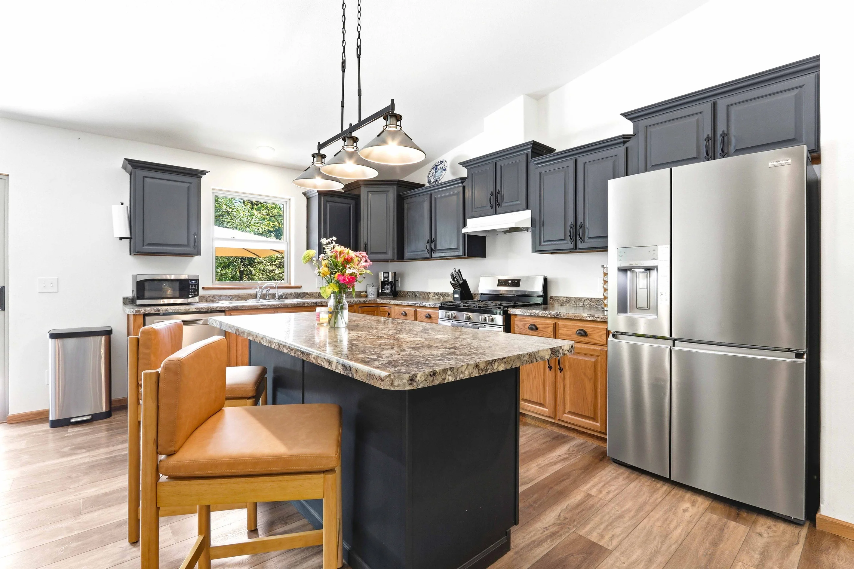 Modern vacation rental kitchen with granite island and stainless steel appliances near Lake Petenwell, Nekoosa