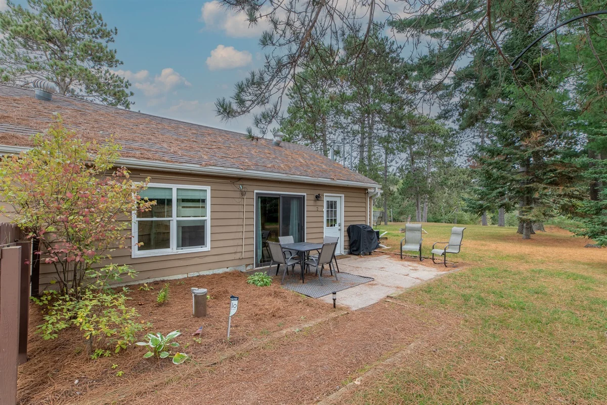 Cottage exterior with patio seating and pine trees, downtown Minocqua lodging walkable area