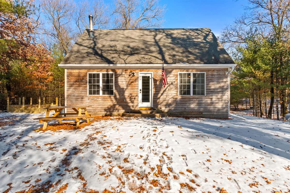 Rustic cabin exterior with natural wood siding, dark roof, and autumn trees at Pickles Cabin in Nekoosa