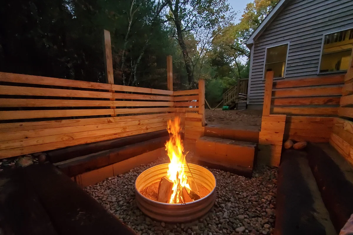 Metal fire pit with active flames and wooden bench seating on Pickles Cabin patio near Lake Petenwell