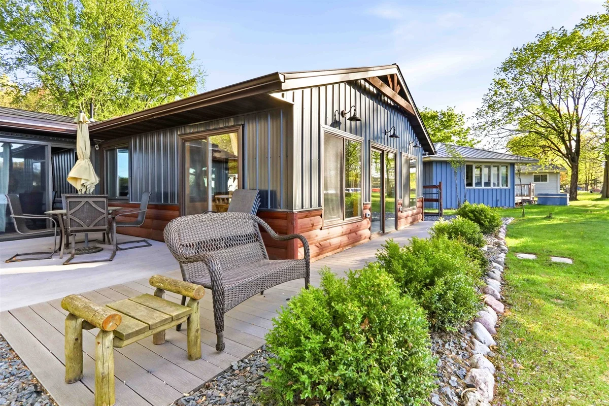 Modern Wisconsin cabin exterior with patio seating and corrugated metal siding in Nekoosa