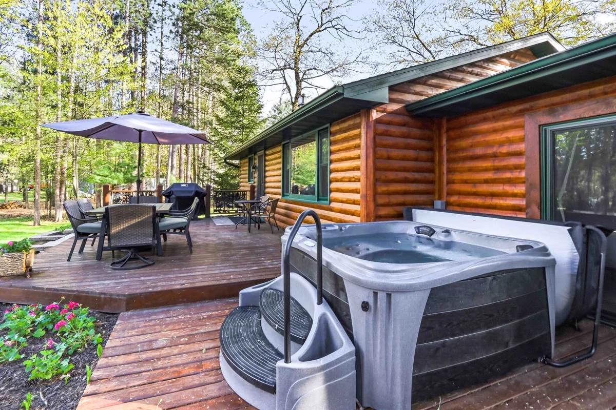 Outdoor patio hot tub and deck with log cabin, ideal for Wisconsin cabin rental booking checklist near Nekoosa