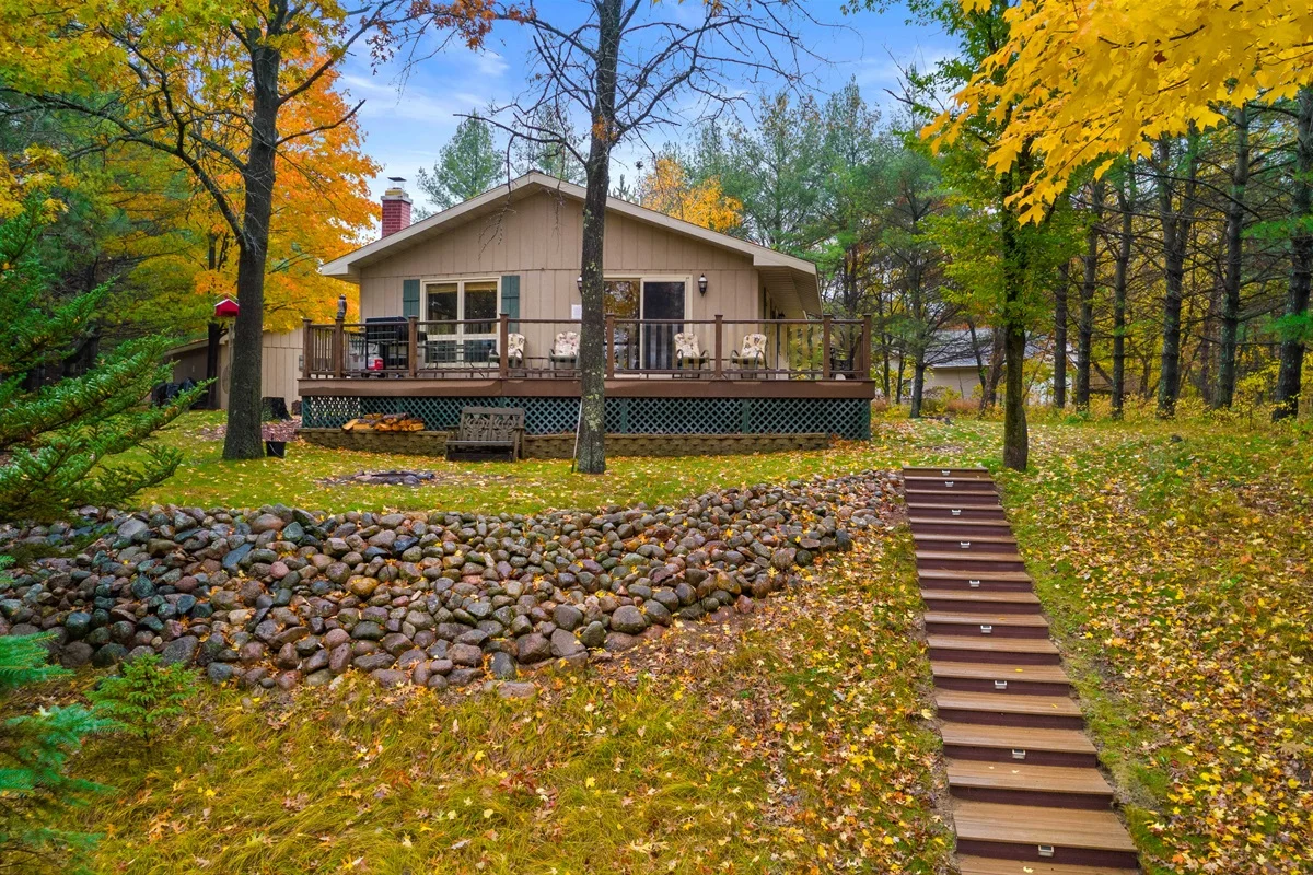 Beige woodland cabin with wraparound deck and autumn foliage, Dune path to the beach near Door County cottage rentals in
