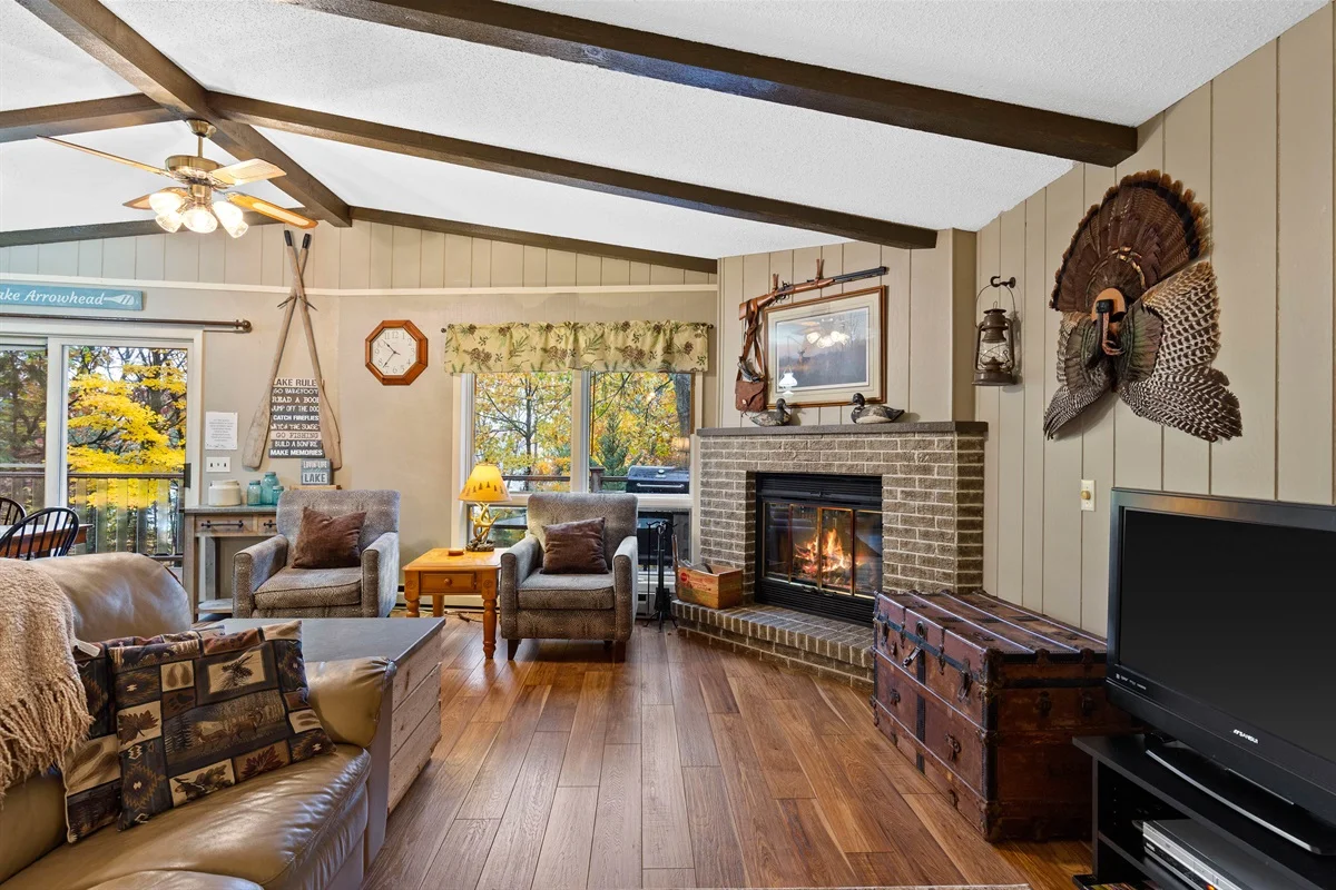 Rustic cabin living room with fireplace, exposed beams and lake views in Minocqua