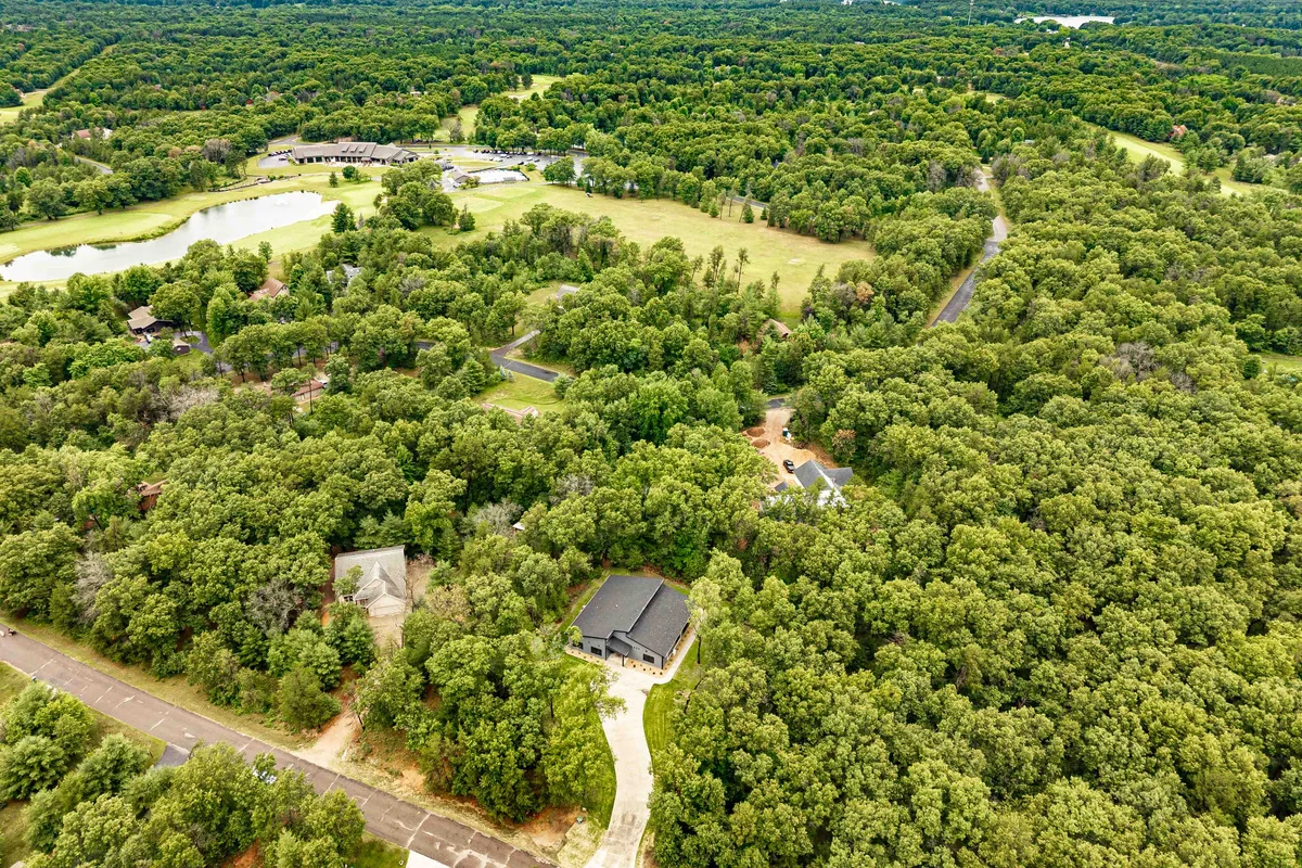 Aerial drone view of a lakefront property in dense forest with winding roads and distant lakes, Northwoods hiking near